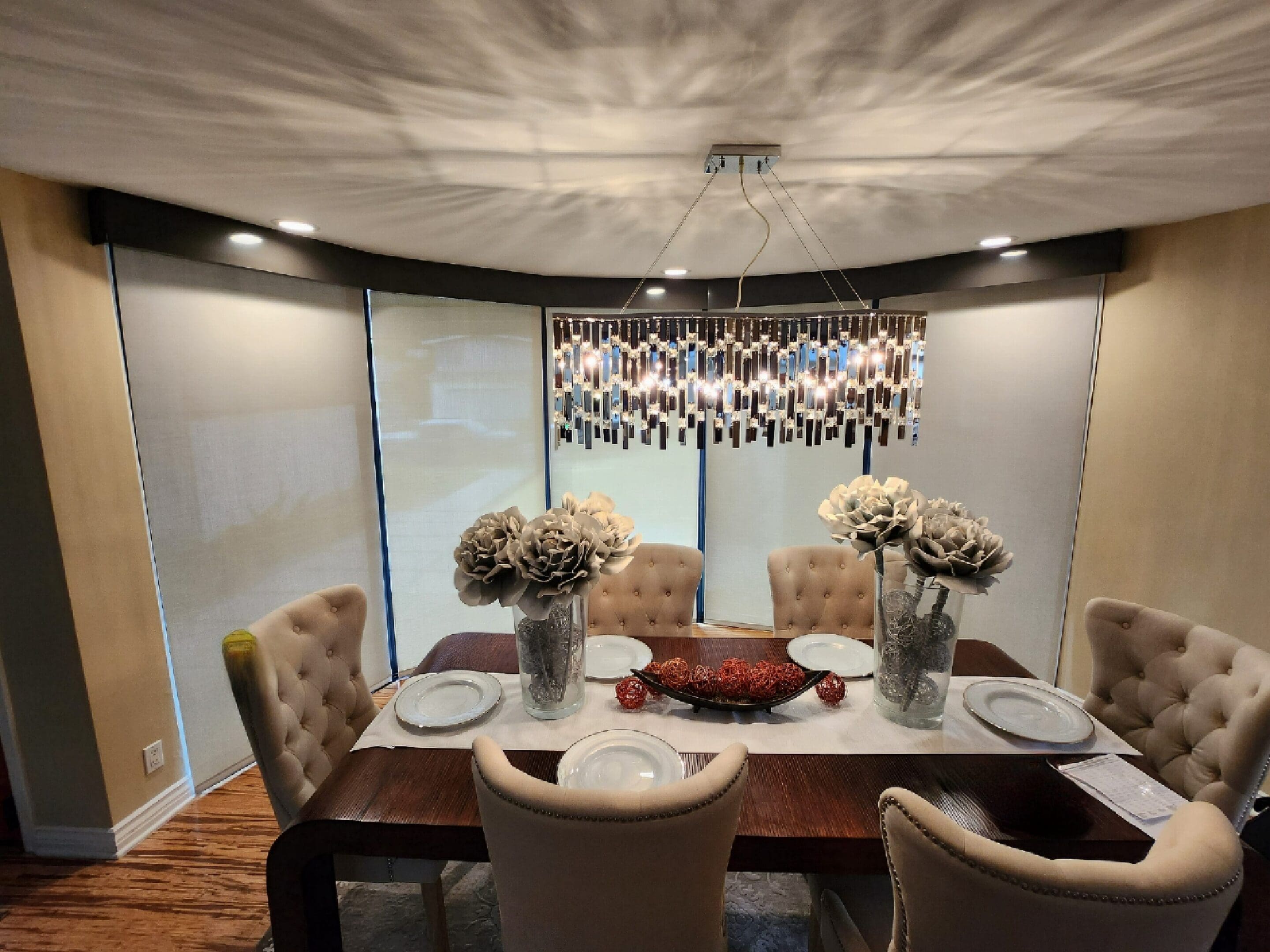 A dining room table with six chairs and a vase of flowers.